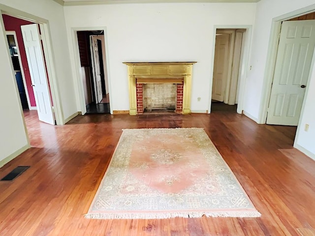 905 Fm 353, San Augustine, TX 75972 - unfurnished living room with baseboards, visible vents, wood finished floors, and a fireplace