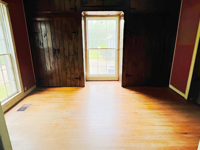 905 Fm 353, San Augustine, TX 75972 - spare room featuring wood walls, baseboards, light wood-type flooring, and visible vents