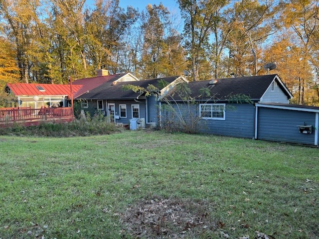 back of property featuring a lawn and a wooden deck