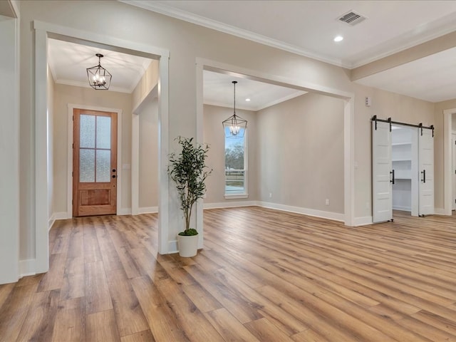 entryway with light wood-type flooring, a barn door, visible vents, and a chandelier