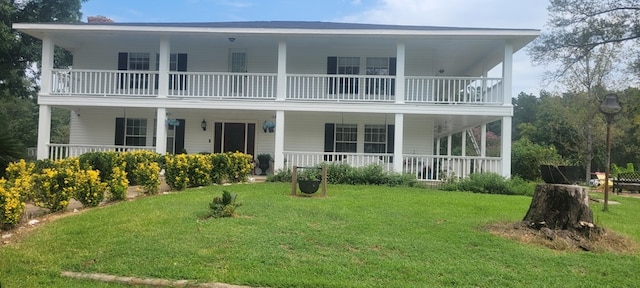 rear view of property featuring a balcony, a porch, and a lawn