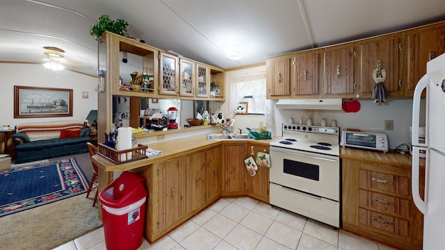 kitchen featuring white appliances, sink, vaulted ceiling, light tile patterned flooring, and kitchen peninsula