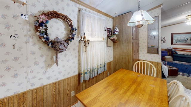 dining space featuring crown molding and wood walls