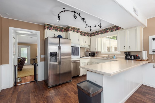 1405 Cimmarron St, Lufkin, TX 75904 - kitchen with stainless steel appliances, a peninsula, light countertops, dark wood-style floors, and a sink