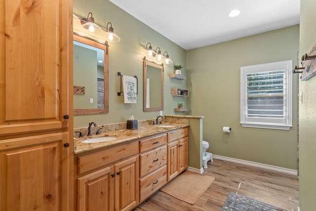 185 Ashley Dr, Brookeland, TX 75931 - bathroom with wood finished floors, toilet, double vanity, and baseboards