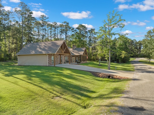 185 Ashley Dr, Brookeland, TX 75931 - view of front of house with a front lawn, a chimney, and view of wooded area