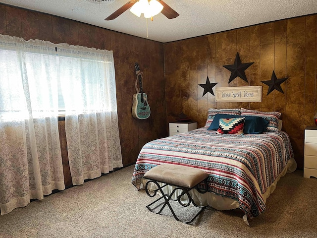 bedroom with ceiling fan, wooden walls, carpet floors, and a textured ceiling