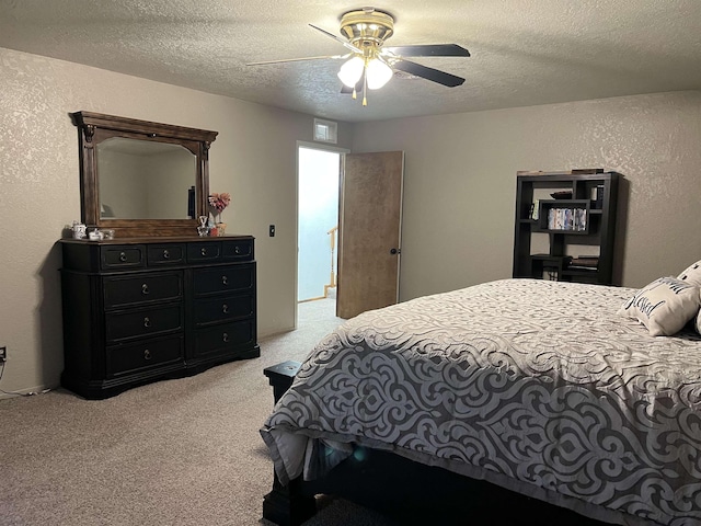 bedroom with ceiling fan, light colored carpet, and a textured ceiling