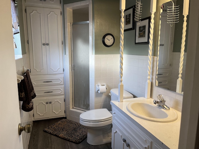 bathroom with vanity, a shower with door, hardwood / wood-style flooring, toilet, and tile walls