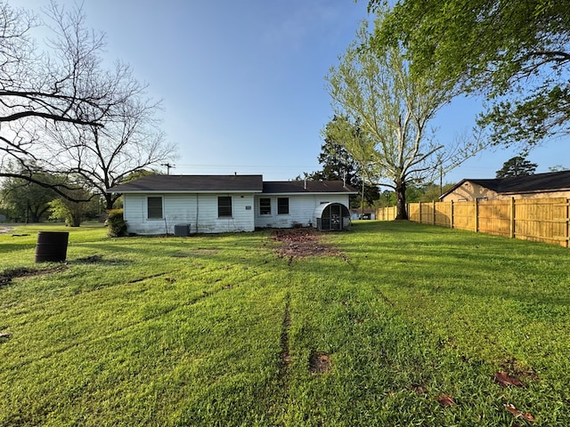 back of property featuring a lawn, fence, and central AC