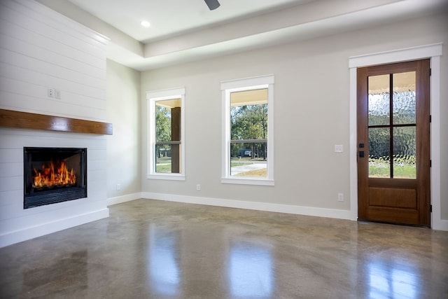 unfurnished living room featuring a wealth of natural light, a large fireplace, and ceiling fan