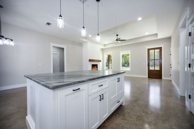 kitchen with pendant lighting, dark stone counters, white cabinets, ceiling fan, and a kitchen island