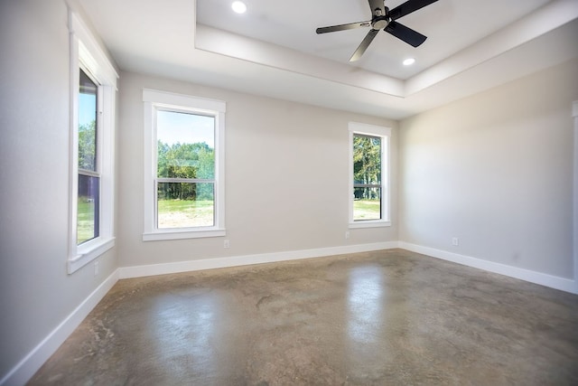 spare room featuring ceiling fan, a raised ceiling, and concrete flooring