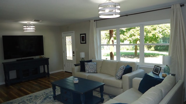 living room featuring a healthy amount of sunlight, dark wood-type flooring, and a chandelier