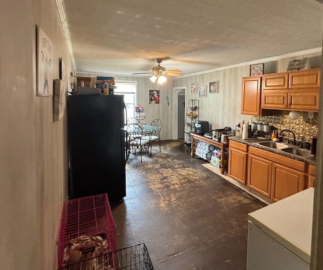 kitchen featuring black fridge, sink, ceiling fan, ornamental molding, and tasteful backsplash