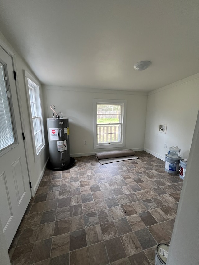 interior space featuring baseboards, electric water heater, crown molding, and stone finish floor