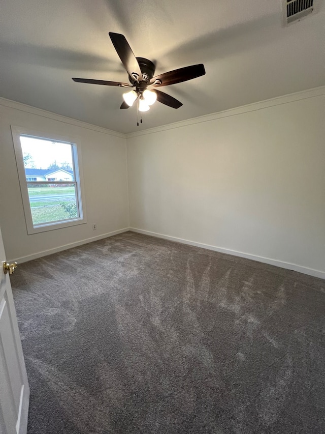 carpeted spare room featuring crown molding, baseboards, visible vents, and ceiling fan