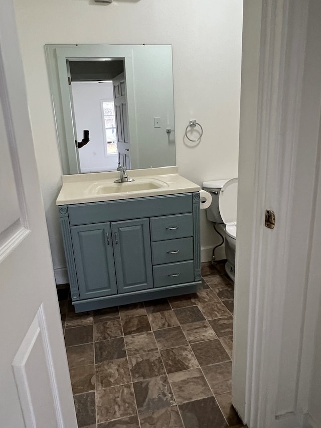 bathroom with vanity, toilet, and baseboards