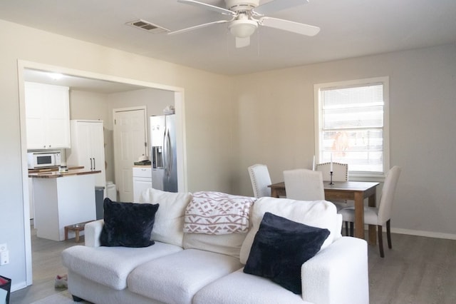 living area featuring ceiling fan, wood finished floors, visible vents, and baseboards