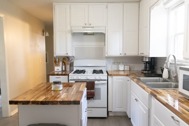 kitchen featuring white cabinets, a sink, butcher block countertops, white appliances, and under cabinet range hood