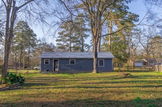 back of house with fence, metal roof, and a lawn