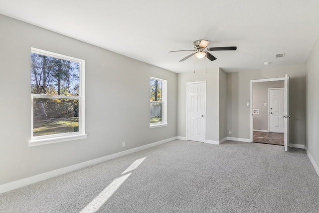 unfurnished bedroom with light carpet, a ceiling fan, visible vents, and baseboards