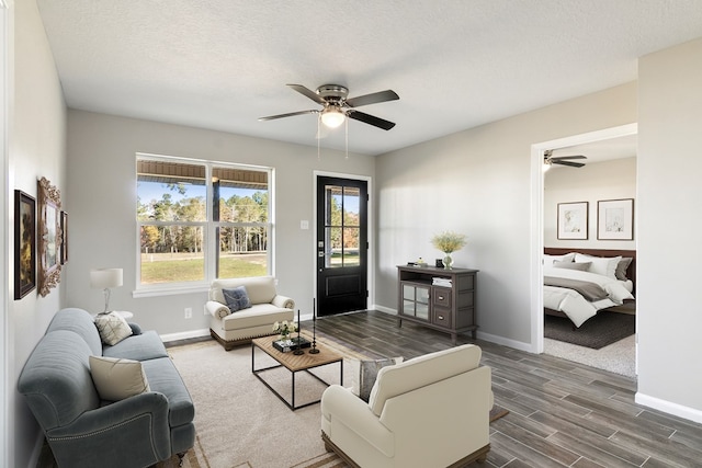 living area featuring a ceiling fan, dark wood finished floors, a textured ceiling, and baseboards