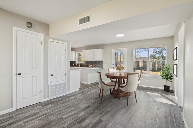 dining room featuring wood tiled floor, visible vents, and baseboards