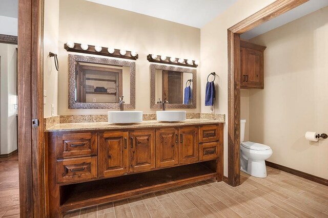 388 County Road 5597, Etoile, TX 75944 - full bathroom featuring wood finished floors, toilet, double vanity, and baseboards