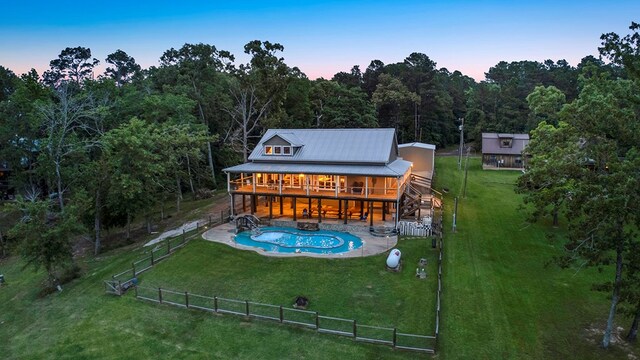 388 County Road 5597, Etoile, TX 75944 - back of property at dusk featuring a wooden deck, a view of trees, metal roof, and a patio area