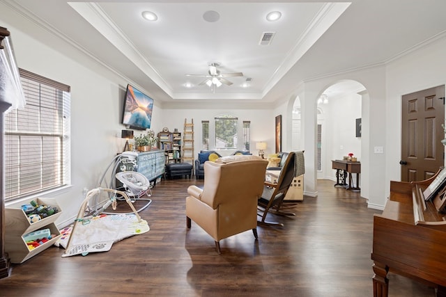 interior space featuring dark hardwood / wood-style floors, ceiling fan, ornamental molding, and a tray ceiling