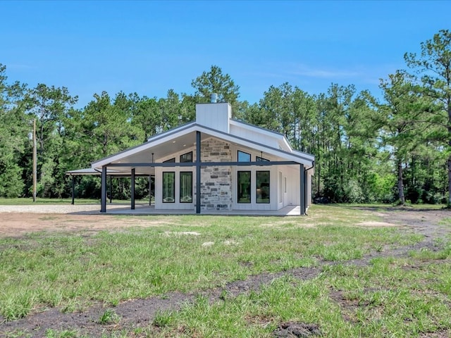 10165 US Highway 287, Corrigan, TX 75939 - rear view of house featuring a chimney, a lawn, board and batten siding, and stone siding