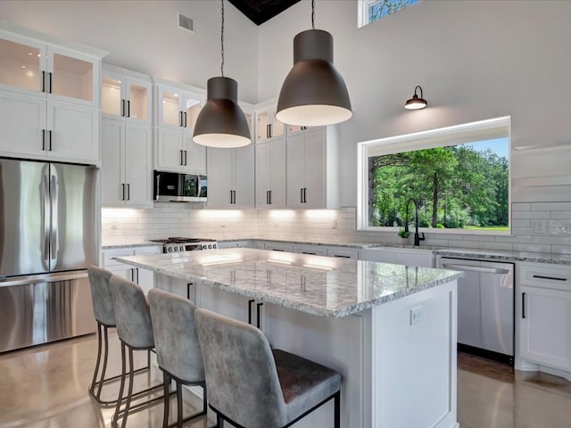 10165 US Highway 287, Corrigan, TX 75939 - kitchen featuring stainless steel appliances, a kitchen island, backsplash, a high ceiling, and white cabinets