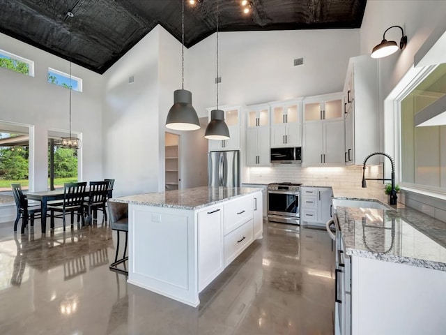 10165 US Highway 287, Corrigan, TX 75939 - kitchen featuring appliances with stainless steel finishes, high vaulted ceiling, decorative backsplash, decorative light fixtures, and light stone counters