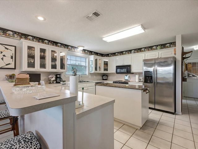 325 Evans Gann Rd, Lufkin, TX 75904 - kitchen featuring stainless steel refrigerator with ice dispenser, black microwave, a peninsula, white cabinetry, and a kitchen island