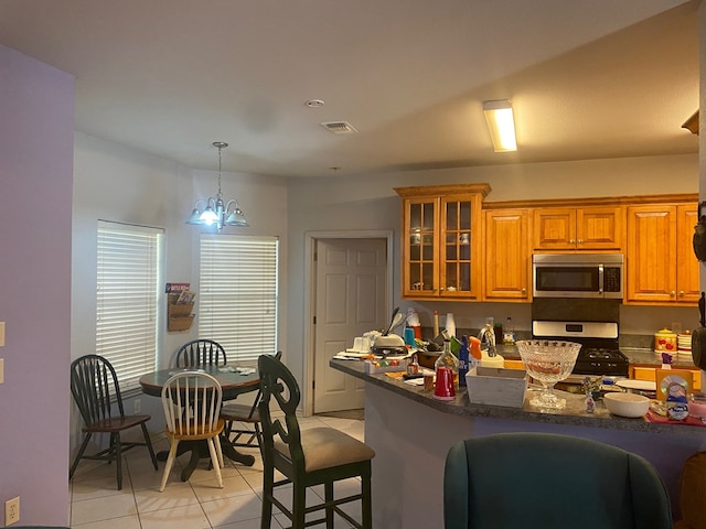 kitchen featuring a breakfast bar, stainless steel appliances, pendant lighting, a chandelier, and light tile patterned flooring