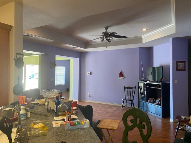 dining space with hardwood / wood-style floors, a raised ceiling, ceiling fan, and crown molding