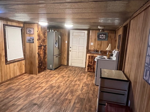 kitchen featuring wood walls, sink, stainless steel fridge, hardwood / wood-style flooring, and white electric range oven