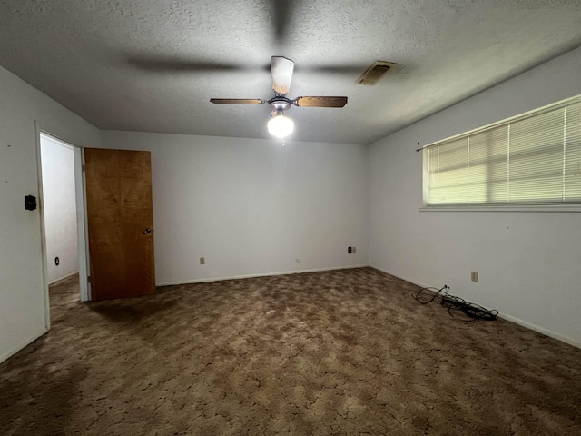 spare room featuring ceiling fan, dark carpet, and a textured ceiling