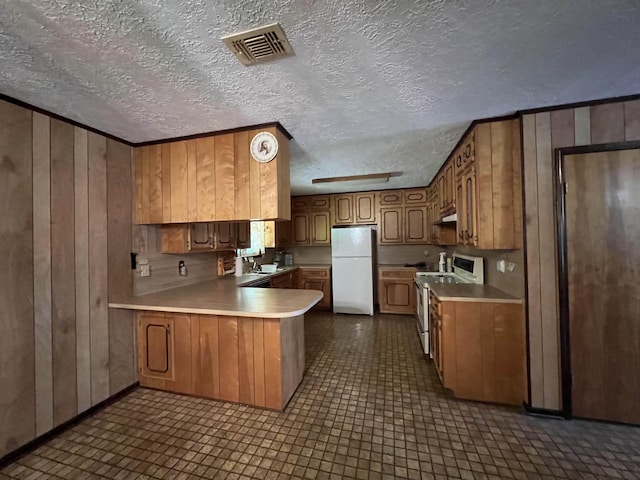 kitchen featuring kitchen peninsula, white fridge, a textured ceiling, wooden walls, and stainless steel range with electric cooktop