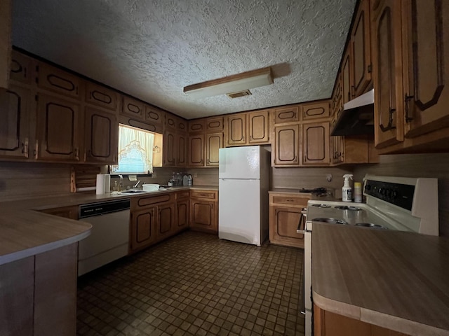 kitchen featuring a textured ceiling, kitchen peninsula, and white appliances