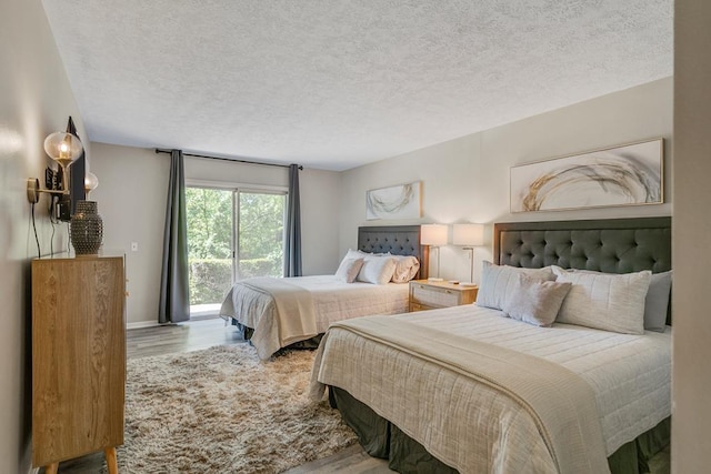 bedroom featuring a textured ceiling, access to outside, and light wood-type flooring