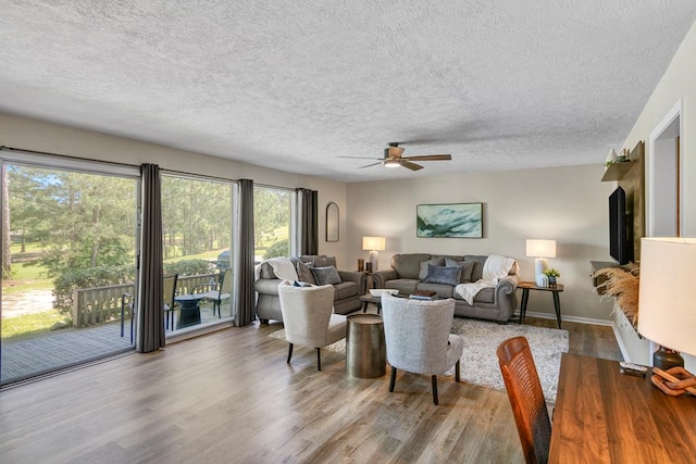 living room with ceiling fan, a textured ceiling, and light wood-type flooring