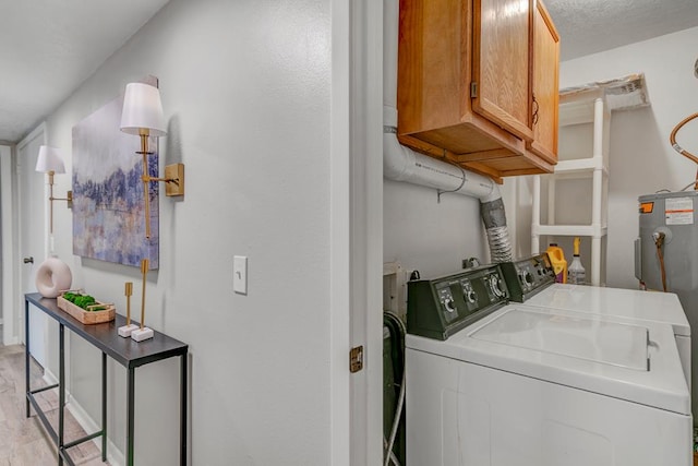 laundry area featuring cabinets, light hardwood / wood-style flooring, washing machine and clothes dryer, and electric water heater