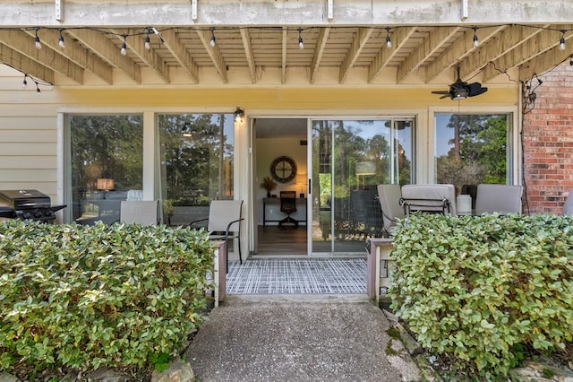 view of exterior entry featuring ceiling fan and a patio