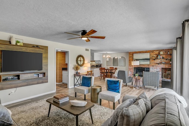 living room with ceiling fan, light wood-type flooring, and a textured ceiling