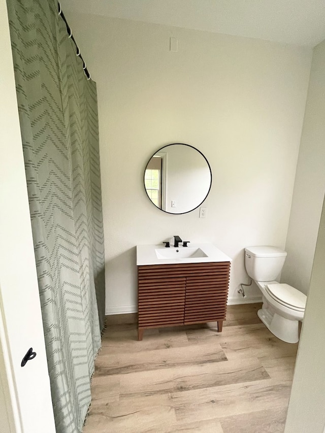 1515 County Road 826, Buna, TX 77612 - bathroom with wood finished floors, toilet, vanity, baseboards, and a shower with shower curtain