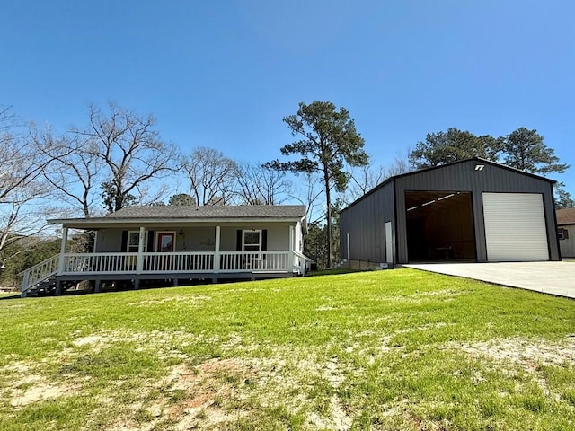 view of front of home featuring covered porch, a front yard, a garage, and an outbuilding