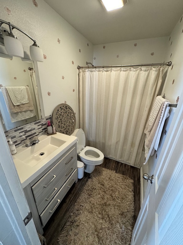 bathroom with curtained shower, toilet, wood finished floors, vanity, and decorative backsplash