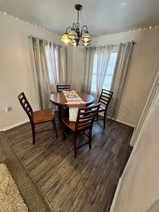 dining room featuring dark wood-type flooring, a chandelier, and baseboards